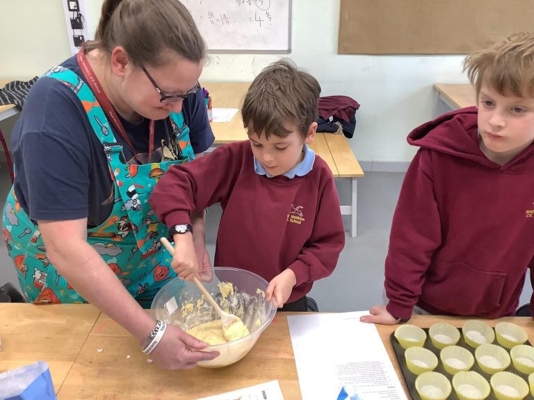 Image of a person helping two children to bake
